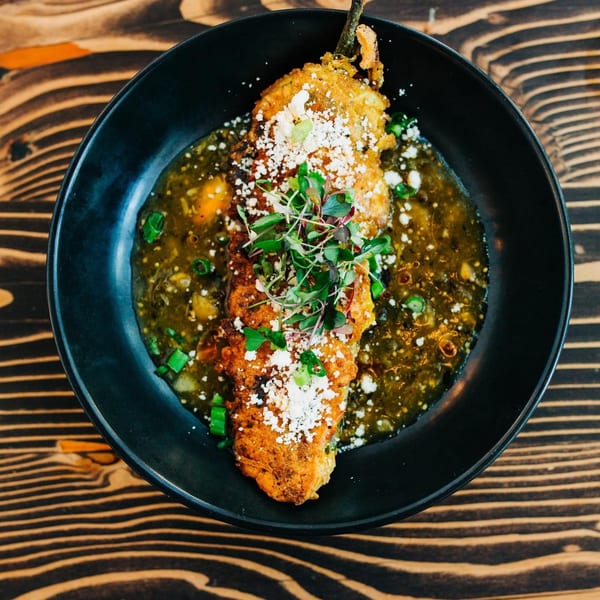 Chula Artisan Eatery's chile relleno, topped with microgreens and cotija cheese, in a green sauce.
