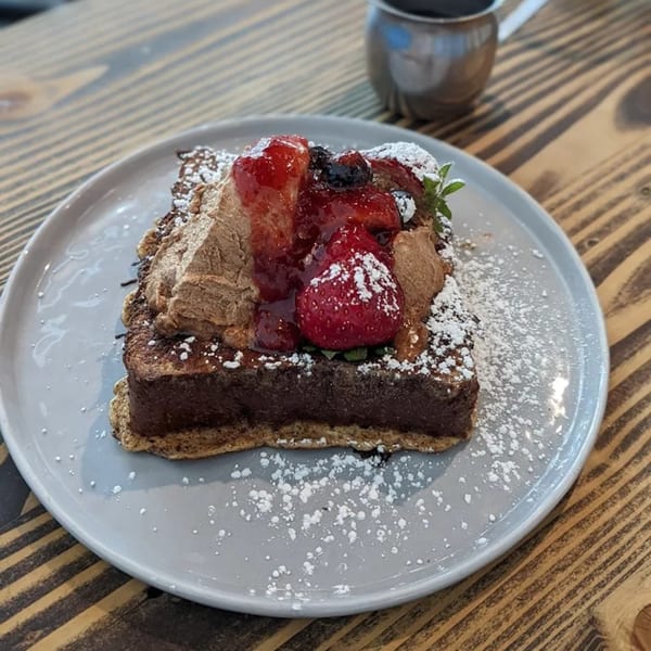 Thick French toast topped with chocolate cream, fresh strawberries, blueberries, and powdered sugar.